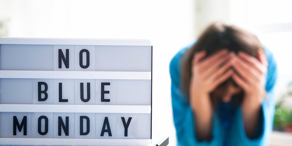 White board with text no blue monday on the table, in the background a woman in blue clothes depress