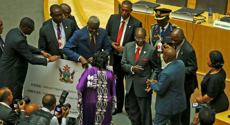 Zimbabwe's President Robert Mugabe, center, gives a $1 million cheque to the African Union during a summit meeting in Addis Ababa, Ethiopia