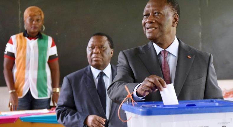 Ivory Coast's President Alassane Ouattara (R) casts his ballot in the presidential election where he seeks a new term on December 18, 2016