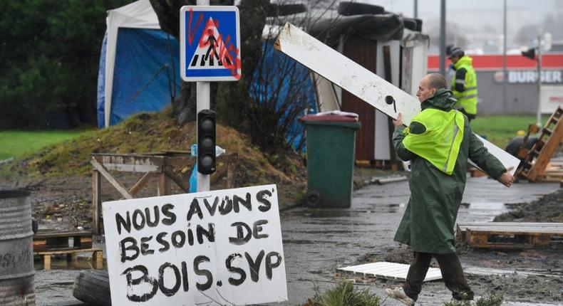 One of the 'yellow vest' protesters helps the construction work at a roundabout in Brest, western France. The sign next to him reads 'We need more wood, please'.