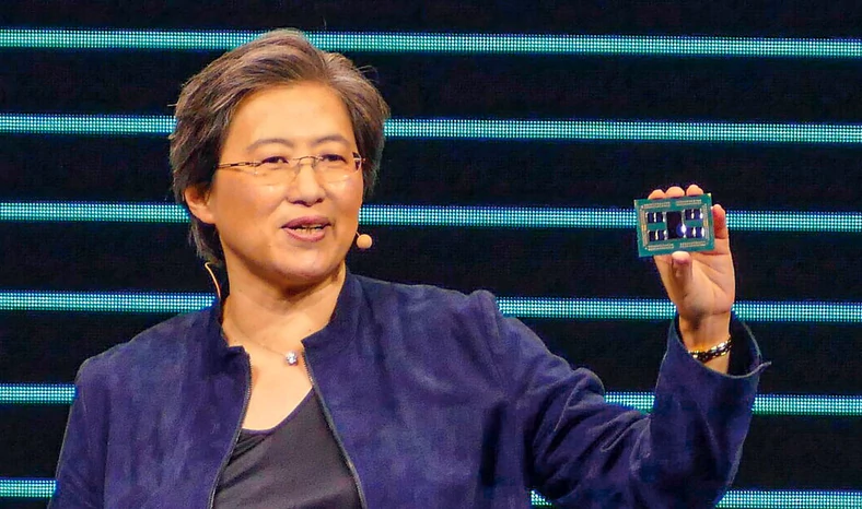 CEO AMD dr Lisa Su z 3990X w dłoni. Widać osiem rdzeni zgrupowanych wokół dużego kontrolera z pamięcią operacyjną i łączem PCI Express
