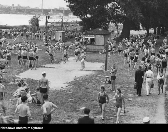 Wakacje w przedwojennej Polsce (na zdjęciu: Plaża Braci Kozłowskich w Warszawie. Widoczny most Poniatowskiego, ludzie na plaży, na Wiśle kajaki. Na plaży budka "Napoje gazowane" w 1936 r.)