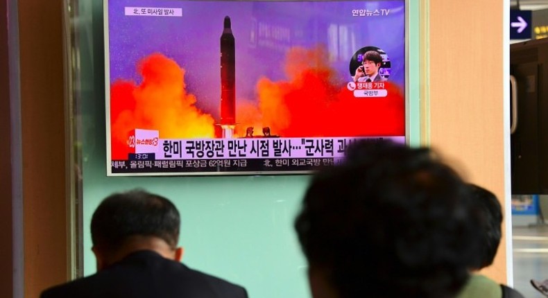 People watch a television news report showing file footage of North Korea's missile launch at a railway station in Seoul on October 20, 2016