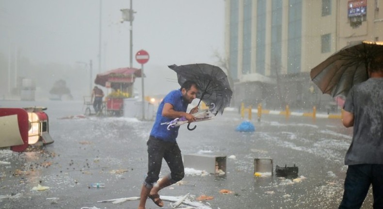 A man holds an umrella during a heavy downpour of hail at Taksim in Istanbul on July 27, 2017