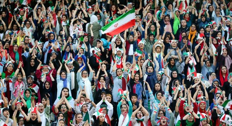 Wearing sporty hats and the national flag, Iranian women cheer for their team at a game they will never forget.