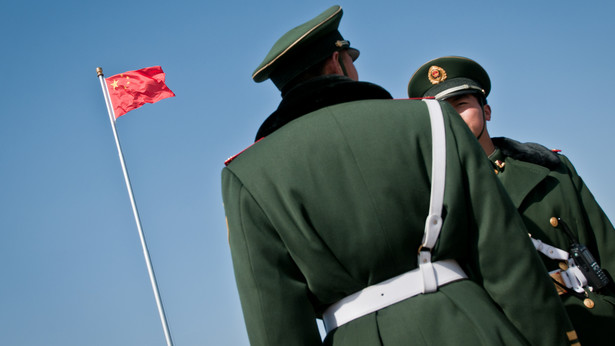 Chińscy żołnierze przed flagą na placu Tiananmen w Pekinie