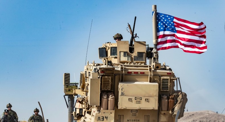 A US soldier sits atop an armored vehicle during a demonstration by Syrian Kurds in the town of Ras al-Ain shortly before the Turkish invasion in October 2019