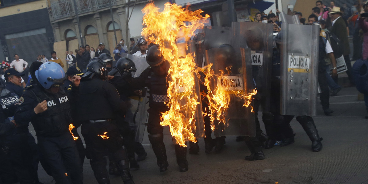 Policemen catch fire after being hit by a Molotov cocktail during a protest to mark the eight-month anniversary of the Ayotzinapa students' disappearance in Mexico City, May 26, 2015.