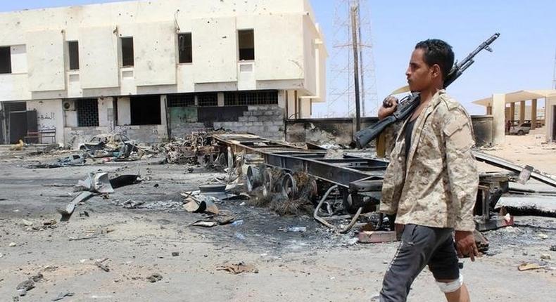 A member of the security team walks past the remains of a burnt car after a suicide car bomber hit a Libyan police station west of the besieged Islamic State stronghold of Sirte June 16, 2016. REUTERS/Stringer