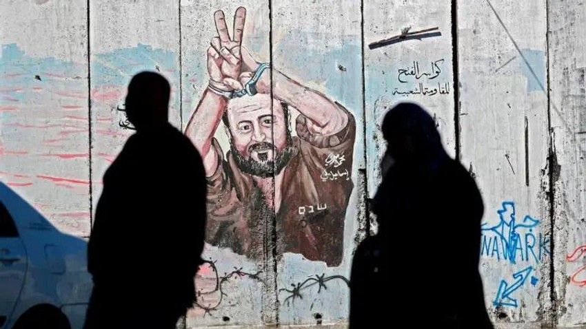Palestinci prolaze pored grafita koji prikazuje palestinskog zatvorenika Marvana Bargutija na izraelskom kontroverznom zidu u Abu Disu, koji razdvaja grad na Zapadnoj obali Abu Dis od Jerusalima | Foto: Getty Images