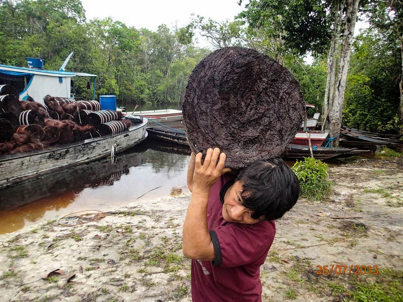 Indianin Yanomami mocujący się z pakunkiem piasawy