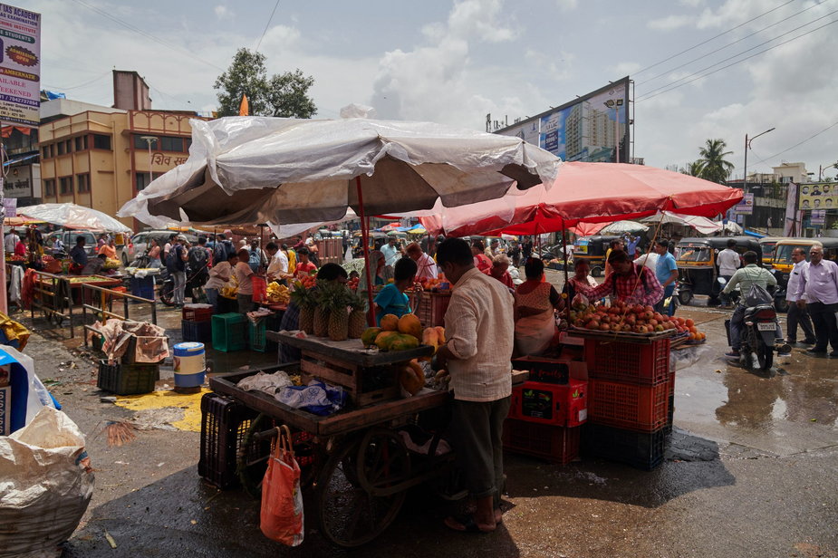 Uliczni sprzedawcy chronią się na straganach przed deszczem podczas pory monsunowej.