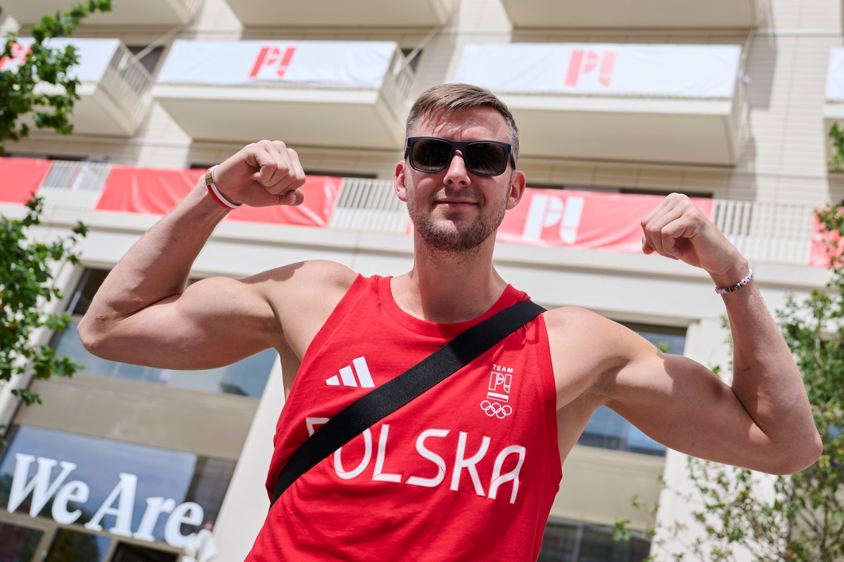 Chorąży polskiej reprezentacji, koszykarz Przemysław Zamojski w wiosce olimpijskiej, na tle budynku, w którym mieszkają nasi sportowcy
