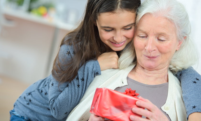 Happy mother's day! adult daughter gives flowers and congratulates an elderly mother on holiday 