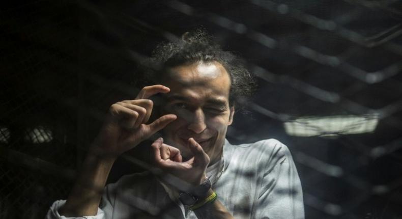 Egyptian photographer Mahmoud Abdel Shakour, known as Shawkan, gestures from inside a soundproof glass dock, during his trial in Cairo on August 9, 2016 