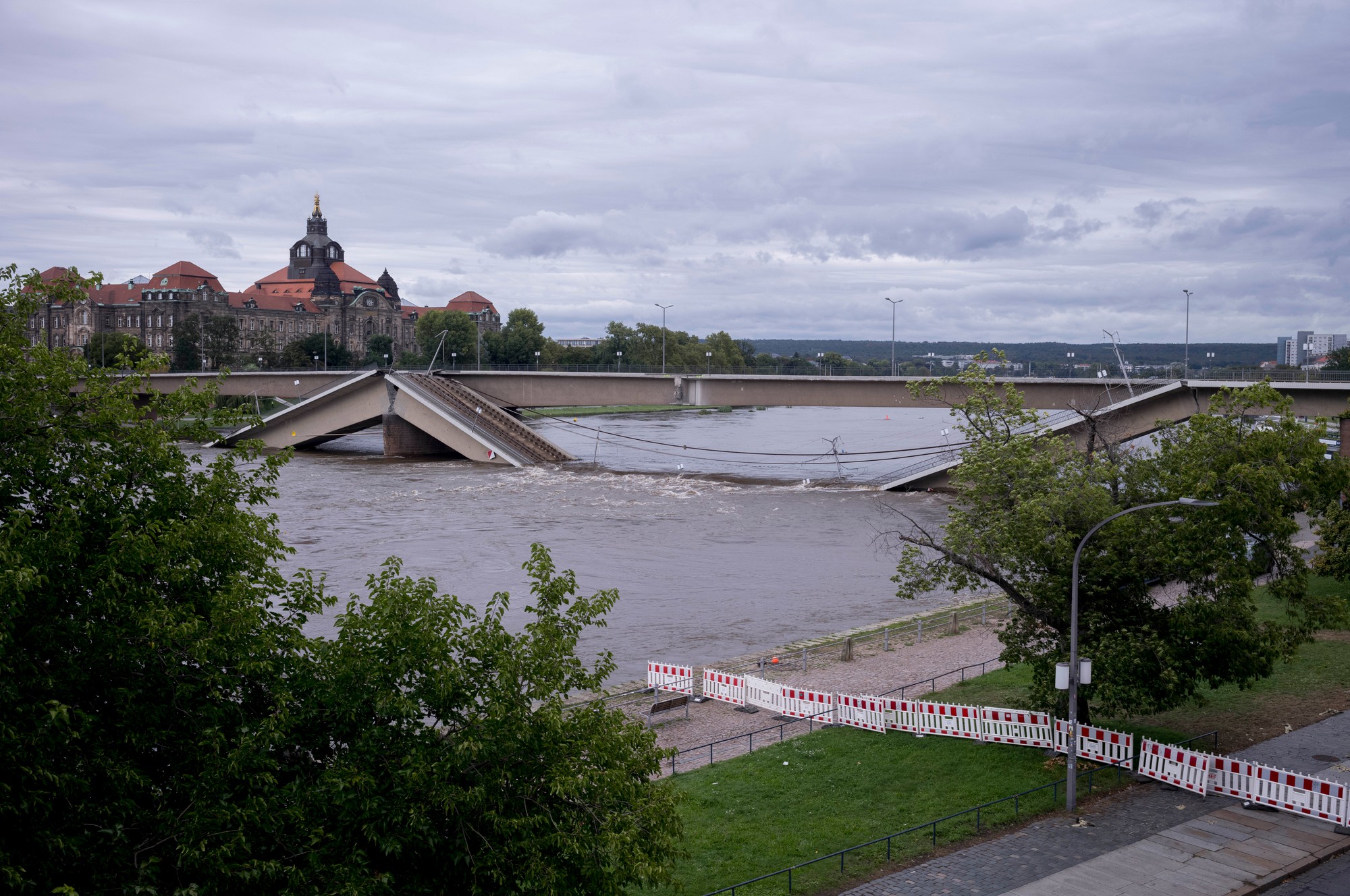 Ľudia a pozerajú na čiastočne zrútený most Carolabrücke na rieke Labe, ktorej hladina stúpa v dôsledku záplav v meste Drážďany.