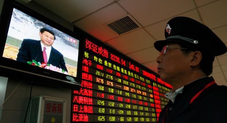 A security guard watches a screen showing newly-elected General Secretary of the Central Committee of the Communist Party of China (CPC) Xi Jinping speaking during a news conference, in front of an electronic board showing stock information at a brokerage house in Huaibei, Anhui province November 15, 2012.