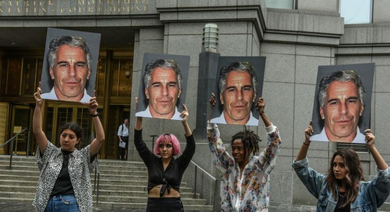 People hold signs of Jeffrey Epstein outside the federal courthouse in New York City on July 8, 2019, as Epstein was charged for sex trafficking minors