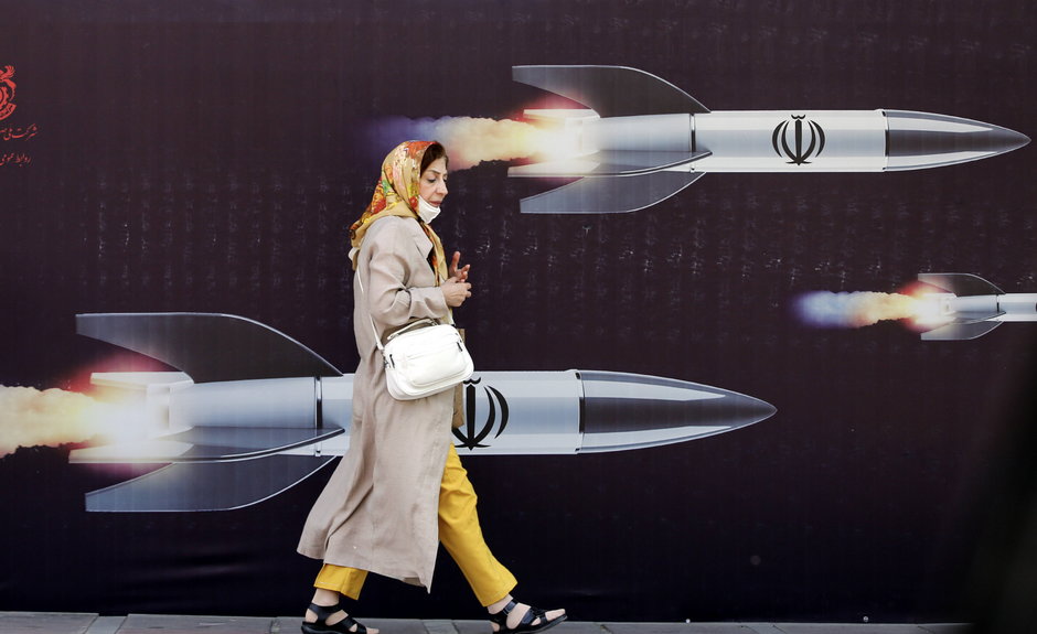 Iranka przechadza się przed antyizraelskim banerem z rakietami, Teheran, 19 kwietnia 2024 r.