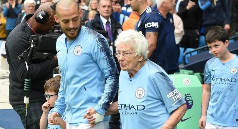 Vera Cohen, a 102-year-old mascot, leads out Manchester City together with David Silva before the English Premier League champions' match at home to Fulham on Saturday