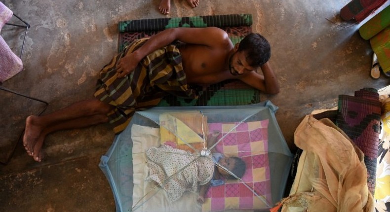 A Sri Lankan child and man rest at a relief camp after being evacuated following flooding Sri Lanka that killed more than 200 people