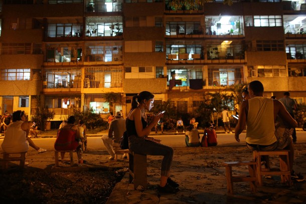 Aguilar uses a mobile phone to connect to the internet at a hotspot in downtown Havana