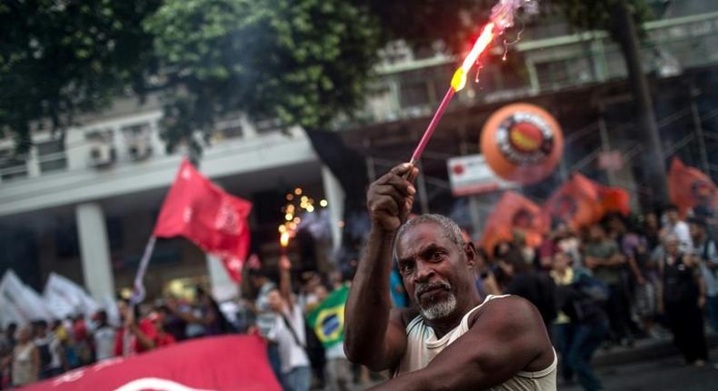 A protester holds fireworks during a demonstration against the Brazilian government's social welfare reform bill in Rio de Janeiro, on March 15, 2017