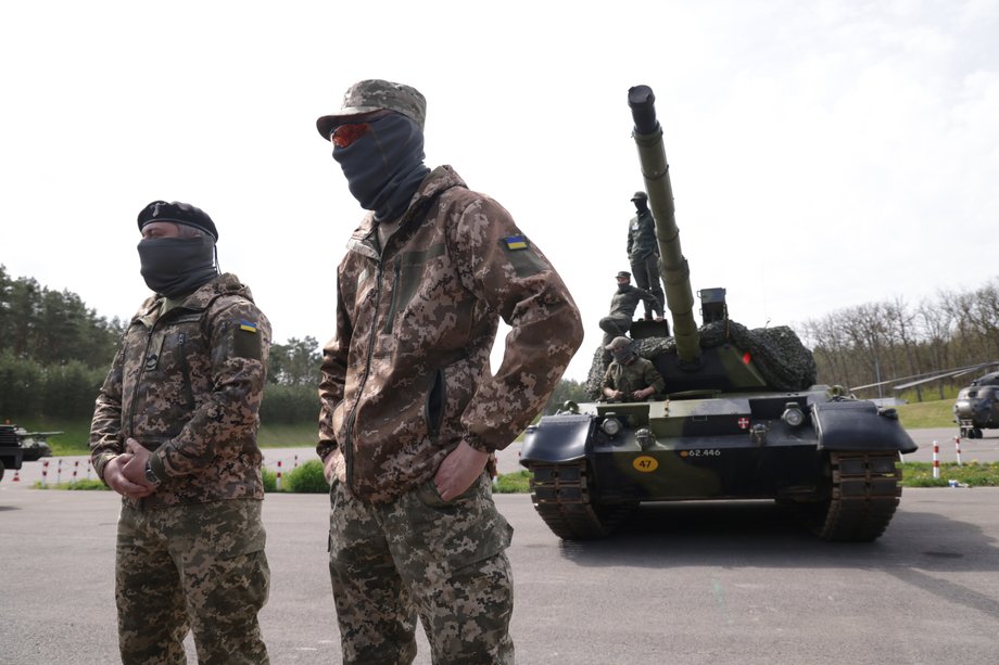 Ukraińska załoga czołgu stoi obok głównego czołgu bojowego Leopard 1A5, którego obsługi i konserwacji szkoli niemiecki i duński personel wojskowy, na poligonie wojskowym Bundeswehry 5 maja 2023 r. w pobliżu Klietz w Niemczech.