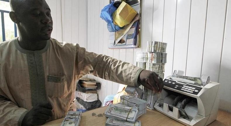 A bureau de change operator counts U.S. hundred dollar notes in Abuja, March 12, 2015. In Nigeria, holding naira has become increasingly unpopular as it has lost its value.  REUTERS/Afolabi Sotunde