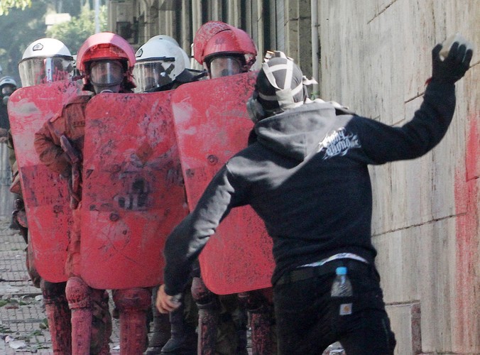 Demonstrant rzuca kamieniem w policjantów pod parlamentem w Atenach
