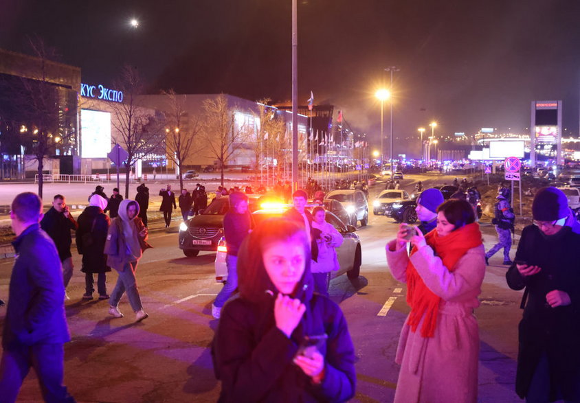 Ludzie zebrani nieopodal płonącej sali koncertowej Crocus City Hall w Moskwie, 22 marca 2024 r.