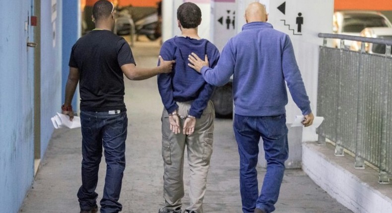 An Israeli-American teenager accused of making dozens of anti-Semitic bomb threats is escorted from an Israeli court in Rishon Lezion on March 23, 2017