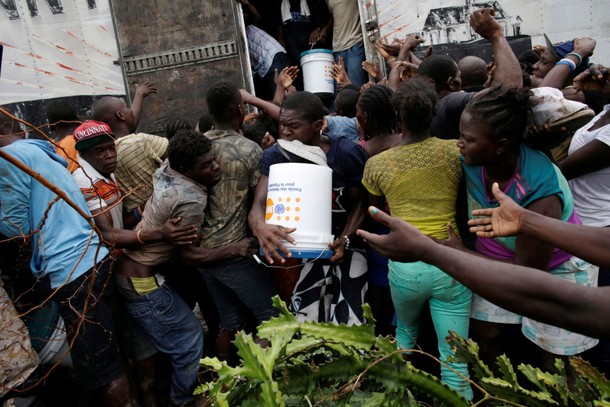 People fight for a bucket of supplies during a distribution after Hurricane Matthew in Torbeck