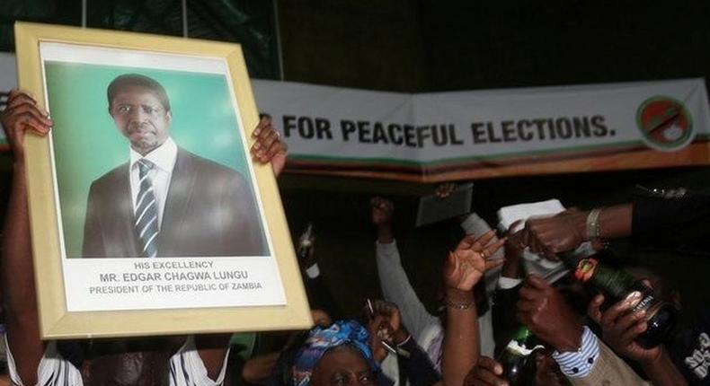 Patriotic Front General Secretary Davies Chama (L) celebrates while holding a portrait of President Edgar Chagwa Lungu after Lungu narrowly won re-election on Monday in the capital, Lusaka, Zambia, August 15, 2016.