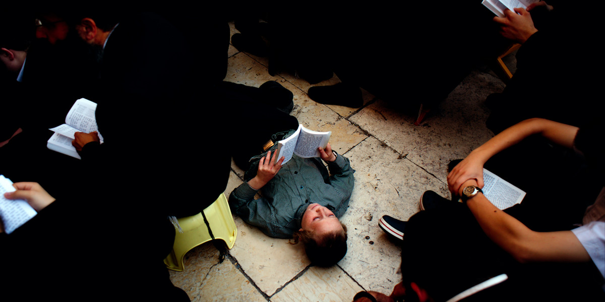 A Hasidic child reads from the Book of Lamentations during a prayer service at the Western Wall for the holiday of Tisha B'Av.