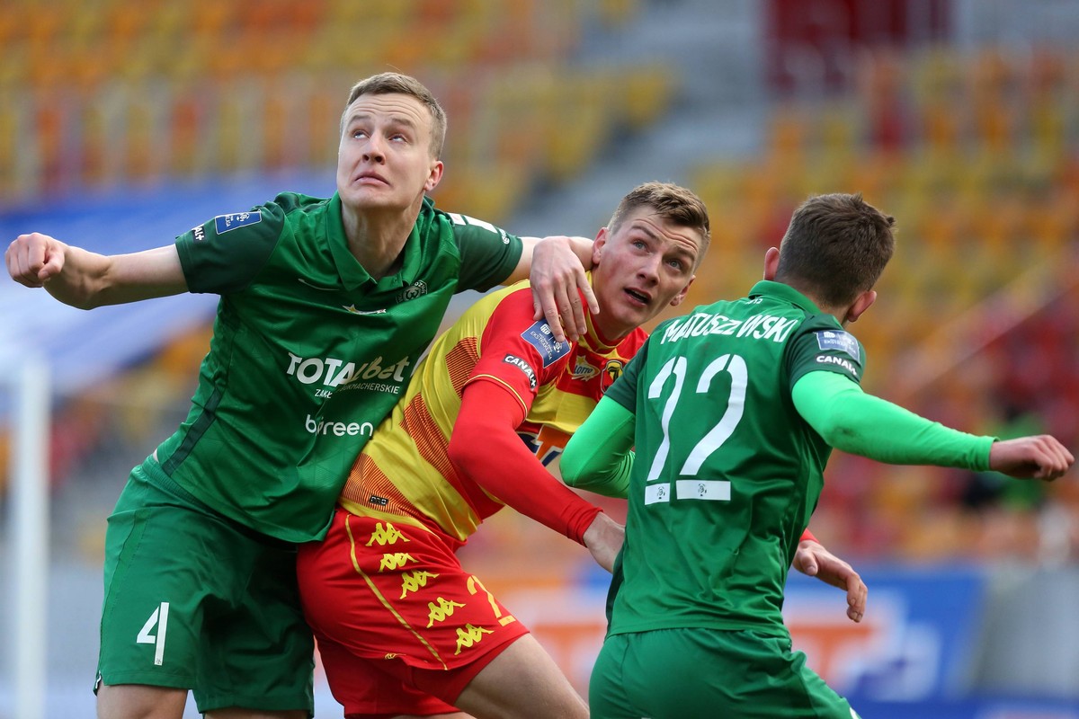 Piłkarze Warty Poznań Robert Ivanov (L) i Konrad Matuszewski (P) w walce o piłkę z zawodnikiem Jagiellonii Białystok Filipem Piszczkiem (C)