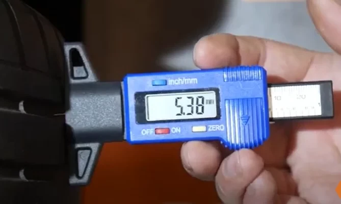 Vodič meria hĺbku dezénu zimnej pneumatiky pred cestou do Rakúska. Minimum pre rakúske cesty je 4 milimetre.