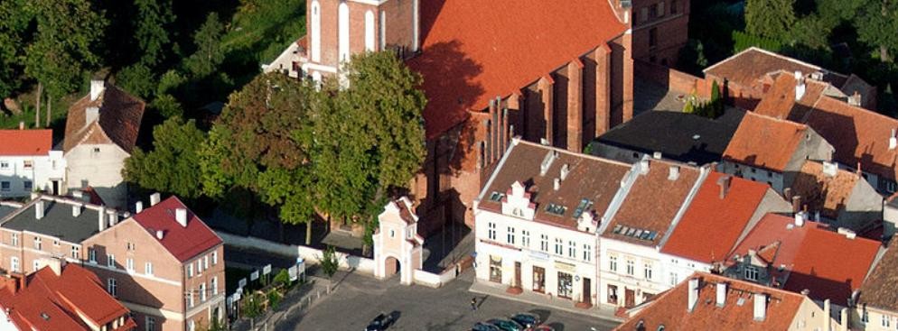 <strong>Jeziorany</strong>
<br></br>
Założycielem Jezioran był biskup warmiński Herman z Pragi, który położył duże zasługi przy uregulowaniu granic biskupstwa i dominium warmińskiego oraz zasiedleniu południowej Warmii. W zastępstwie biskupa przywilej lokacyjny na prawie chełmińskim wystawił w 1338 roku kanonik braniewski Mikołaj i wójt biskupi Henryk von Luter. Zasadźcą został Henryk Wandepfaffe. Miastu przydzielono 110 włók ziemi, z tego 11 włók należało do sołtysa, 6 stanowiło uposażenie kościoła, jedną zarezerwowano jako pastwisko na potrzeby zamku, jedną przeznaczono na zabudowę miasta. Murowany zamek biskupów warmińskich wybudowano po 1350 r. Była to budowla siostrzana do zamku w Reszlu, dwuskrzydłowa z narożną wieżą typu bergfried, poprzedzona od wschodu małym przedzamczem. Zamek rozebrano po pożarze w 1783 r., a materiał przeznaczono na odbudowę miasta. Zachowała się jedynie dolna część głównego skrzydła zachodniego ze sklepionymi piwnicami. Mury obronne miały trzy bramy: Mostową, Młyńska i reszelską, zostały wzniesione po 1360 r. Pożar z 1783 r. zniszczył Jeziorany niemal doszczętnie. Odbudowano je w całości murowane, co na owe czasy było niezwykłe. Wspominał nawet o tym biskup Ignacy Krasicki.
<br></br>
Fot. ZeroJeden / Wikimedia Commons, lic. cc-by-sa