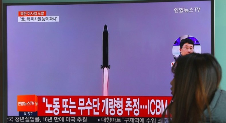 A woman walks past a television screen showing file footage of North Korea's missile launch at a railway station in Seoul on February 12, 2017