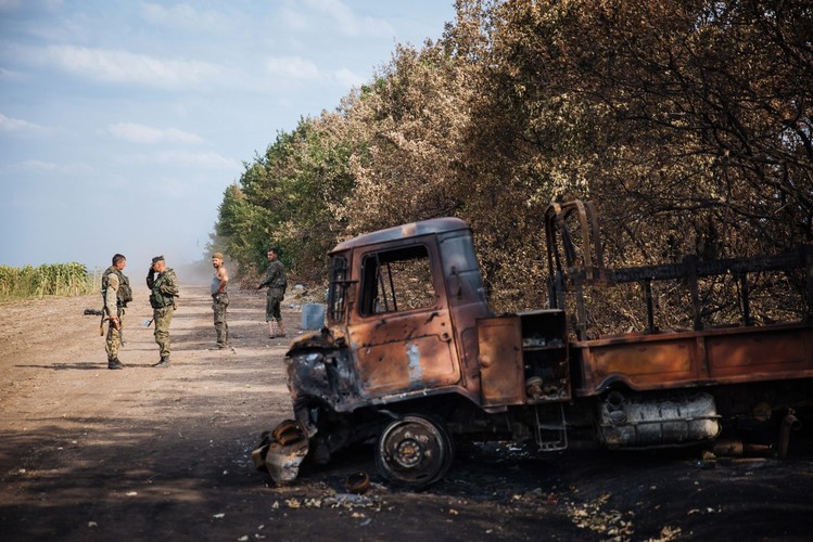 Ukraińscy żołnierze przy spalonym samochodzie w pobliżu bazy wojskowej