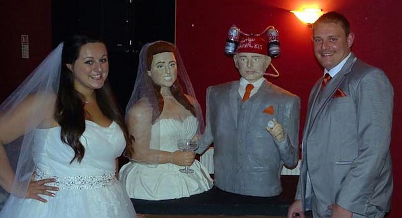 Lara Masone and her groom standing stand by side with their wedding cake made in their likeness