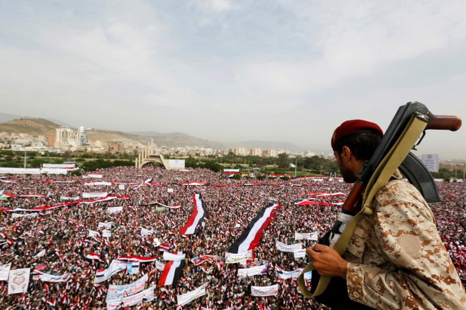 Soldier looks at people rallying to show support to a political council formed by the Houthi movement and the General People's Congress party to unilaterally rule Yemen by both groups, in the capital Sanaa