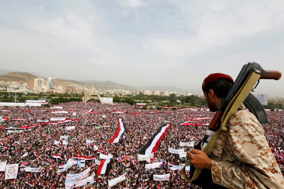 Soldier looks at people rallying to show support to a political council formed by the Houthi movement and the General People's Congress party to unilaterally rule Yemen by both groups, in the capital Sanaa