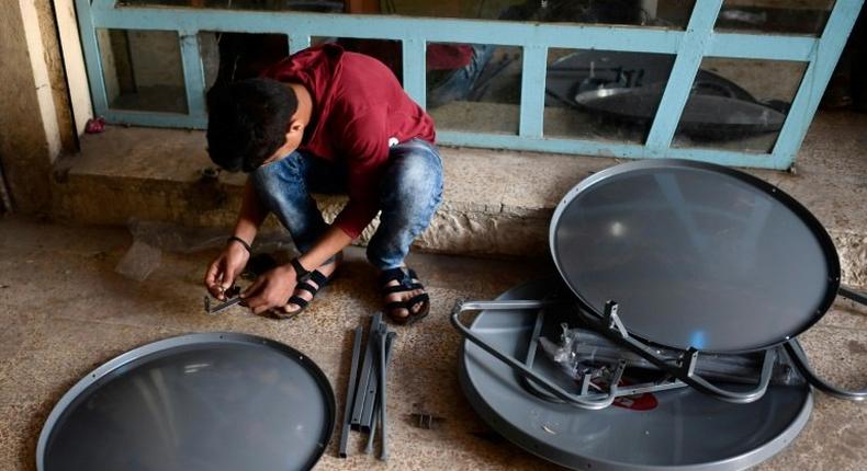 A young Iraqi prepares satellite dishes for sale at a market in east Mosul on April 15, 2017. Since Iraqi forces recaptured the sector from the Islamic State group in January, business has surged