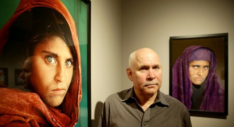 US photographer Steve McCurry poses next to his photos of the Afghan Girl, Sharbat Gula, at a 2013 exhibition in Hamburg, northern Germany