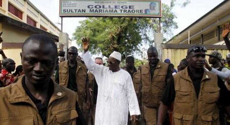 Incumbent president Alpha Conde, leader of Rassemblement du Peuple de Guinea (RPG), wavess as he leaves the polling station during a presidential election in Conakry, Guinea October 11, 2015.