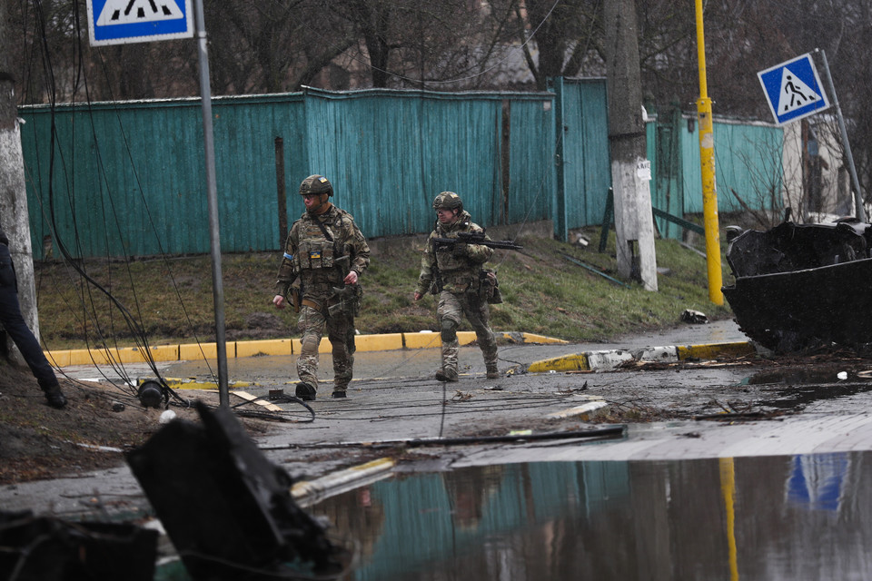 Ukraińscy żołnierze przechodzą obok zniszczonego rosyjskiego sprzętu wojskowego