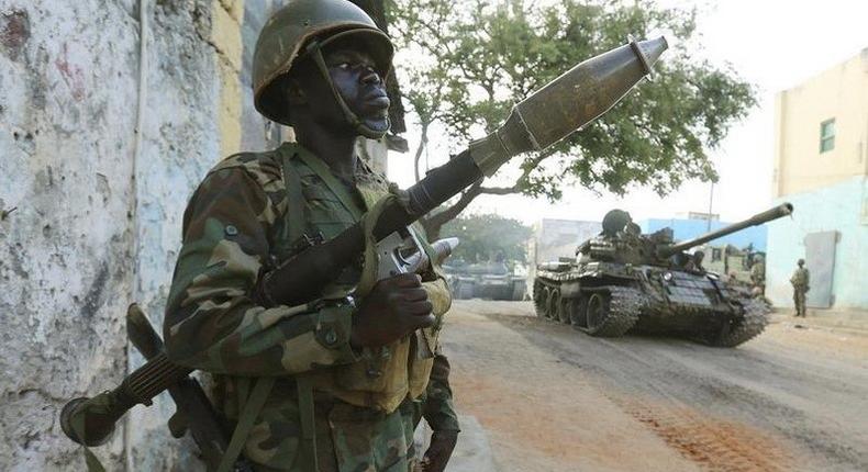 A Somali army soldier keeps guard as a tank rolls past after they captured the town of Barawe during the second phase of Operation Indian Ocean October 6, 2014. REUTERS/Feisal Omar