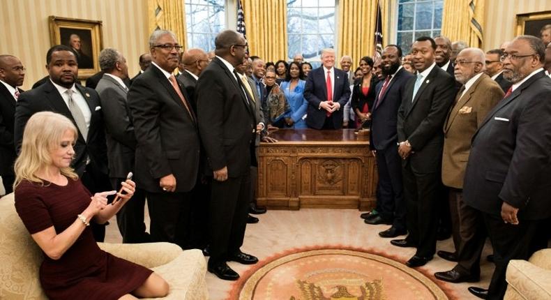 US President Donald Trump's senior advisor Kellyanne Conway (L) checks her phone after taking a photo as Donald Trump hosts leaders of historically black universities and colleges in the Oval Office on February 27, 2017