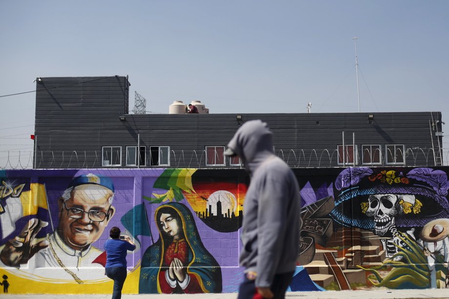 A woman takes photos of graffiti of Pope Francis in Ecatepec, Mexico, February 4, 2016.